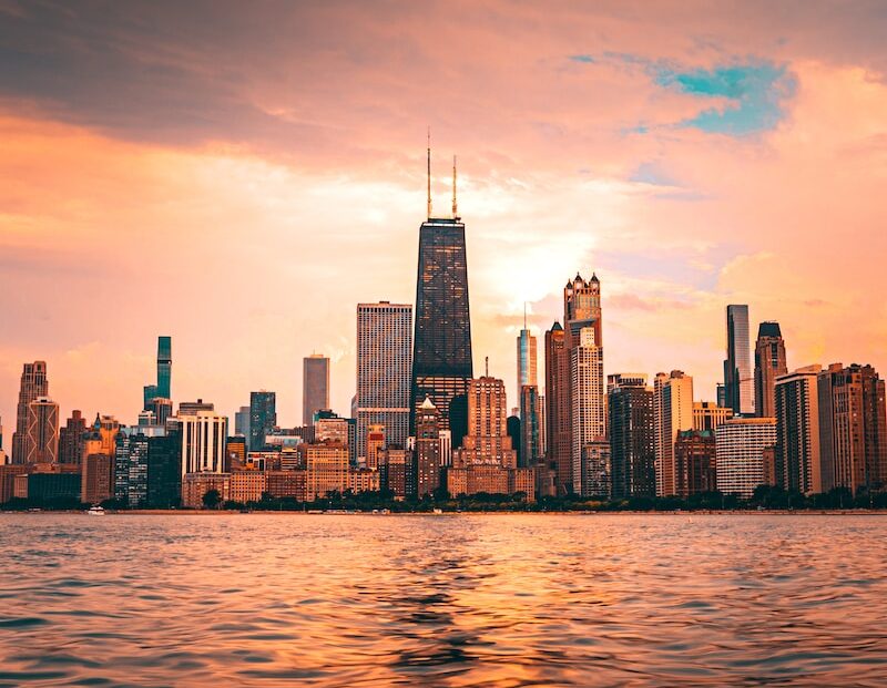 a view of a city from the water at sunset